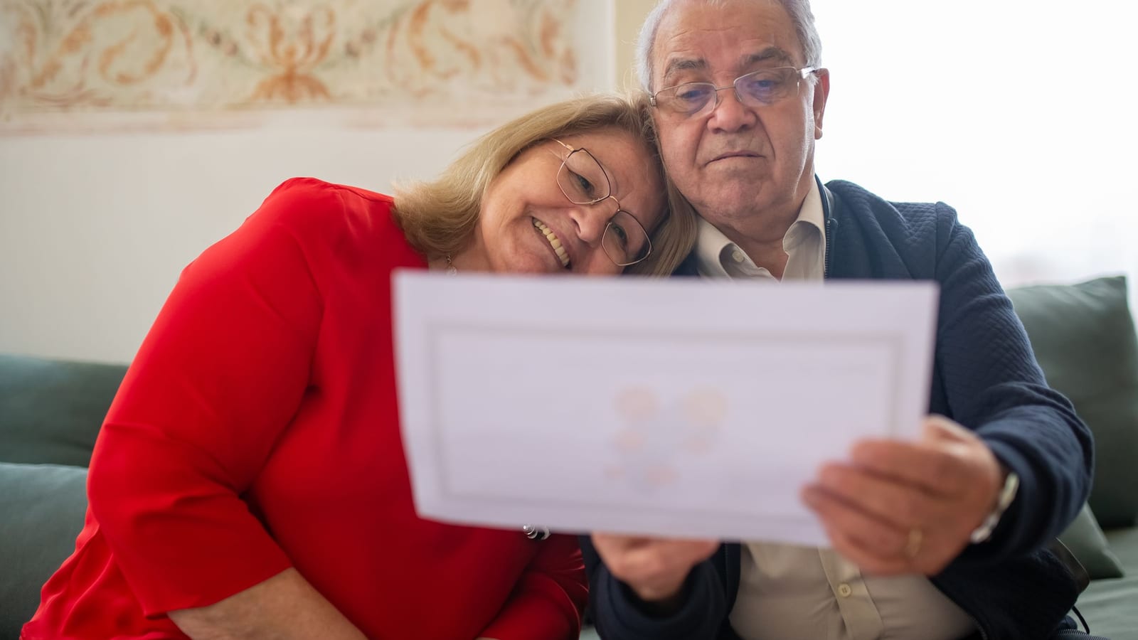Pareja de adultos mayores revisando juntos el aviso anual de cambios de su plan de Medicare en casa